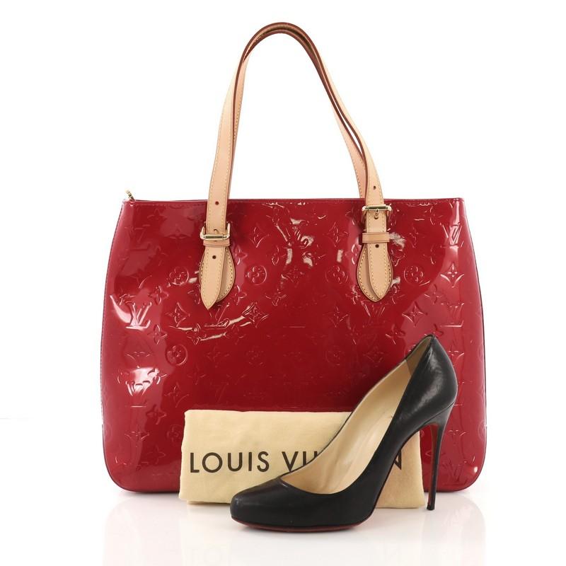 This Louis Vuitton Brentwood Handbag Monogram Vernis, crafted from red monogram embossed vernis leather, features dual flat tall vachetta leather handles, vachetta leather trim, and gold-tone hardware. Its top zip closure opens to a red fabric