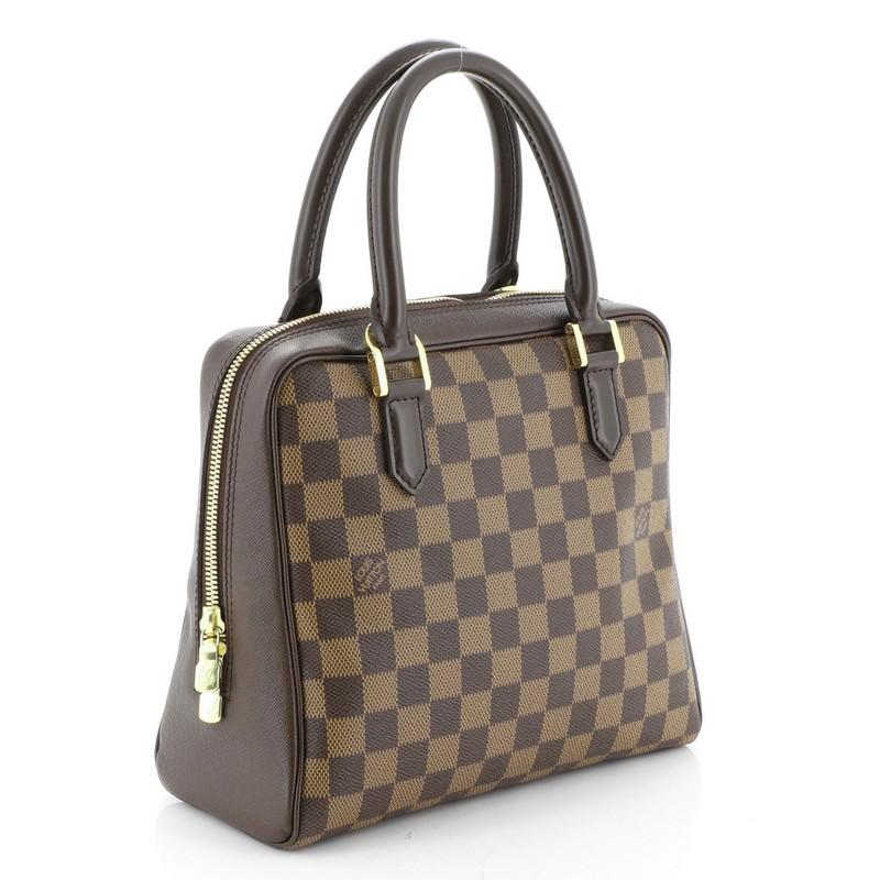 This Louis Vuitton Brera Handbag Damier, crafted from damier ebene coated canvas, features dual rolled leather handles, leather trim and gold-tone hardware. Its two-way zip closure opens to an orange microfiber interior with zip pocket. Authenticity