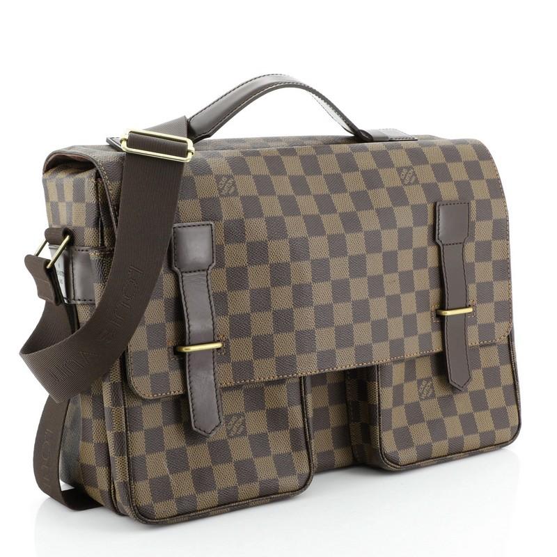 This Louis Vuitton Broadway Bag Damier, crafted in damier ebene coated canvas, features an adjustable cross-body strap, top handle, two pockets under flap, and gold-tone hardware. Its buckle closure opens to a brown fabric interior with slip