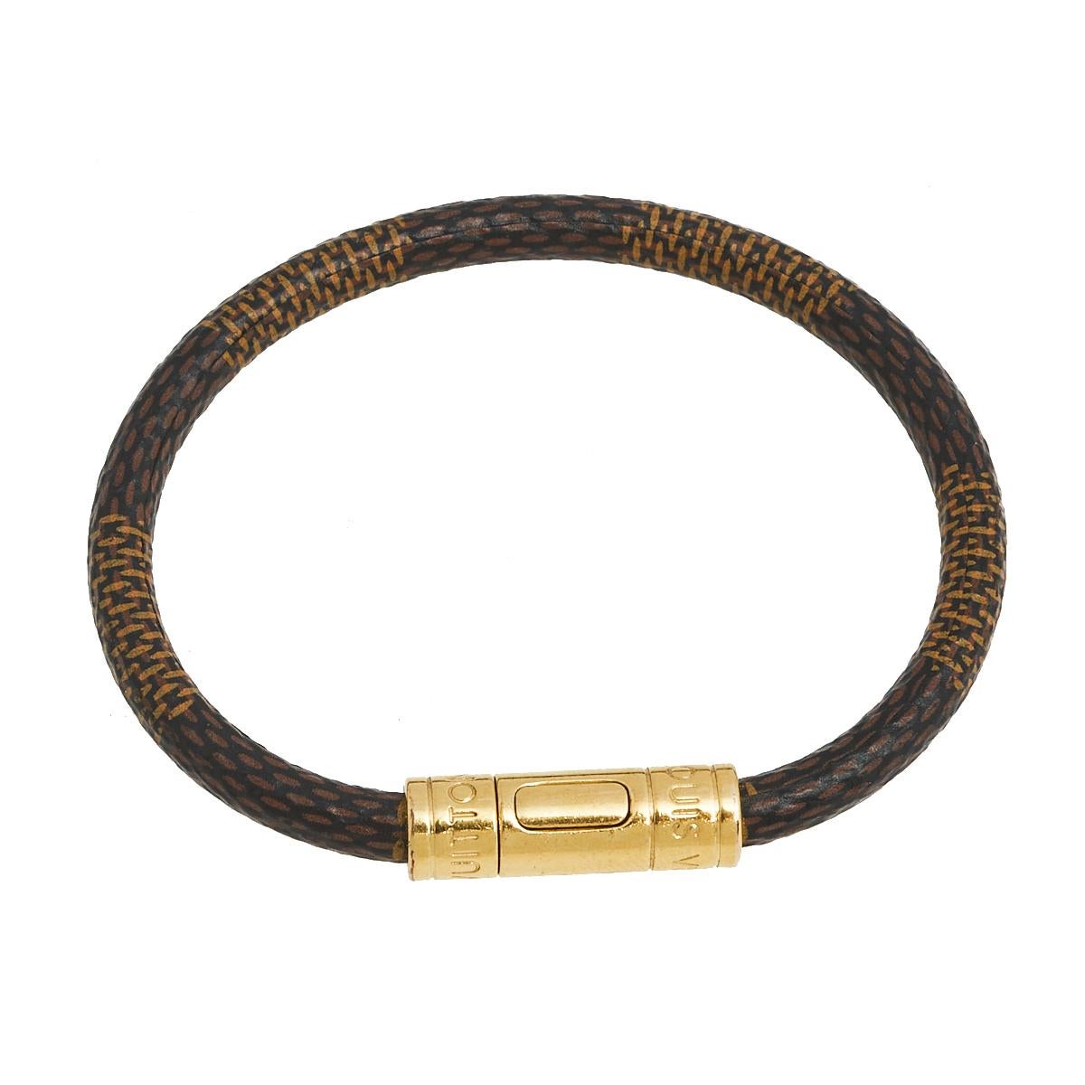 Simple yet elegant, this Louis Vuitton Keep It bracelet is designed with the label's Damier Ebene canvas and features a gold-tone metal closure. Wear it as a stand-alone piece or stack it with similar bands for a layered effect.