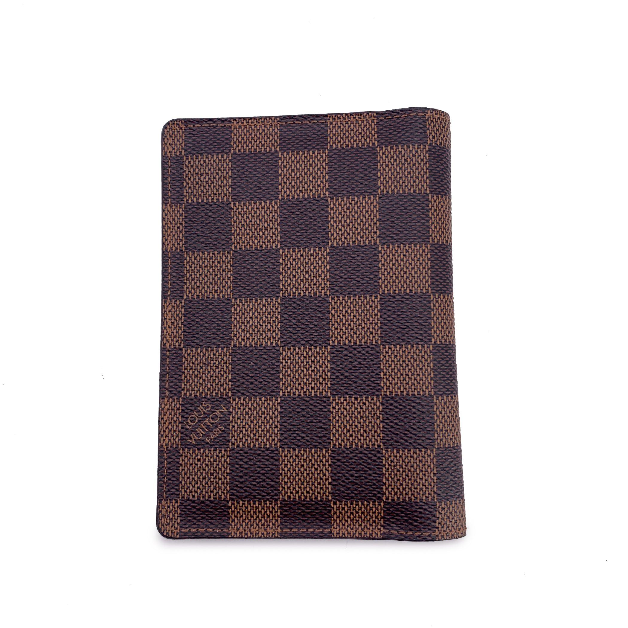 Passport holder in Damier Ebene canvas by Louis Vuitton. Leather lining. Inside it has space for a passport, open pockets and 3 card slots.'Louis Vuitton Paris - Made in Spain' embossed inside. Data code embossed inside. Retail Price: $320 Condition