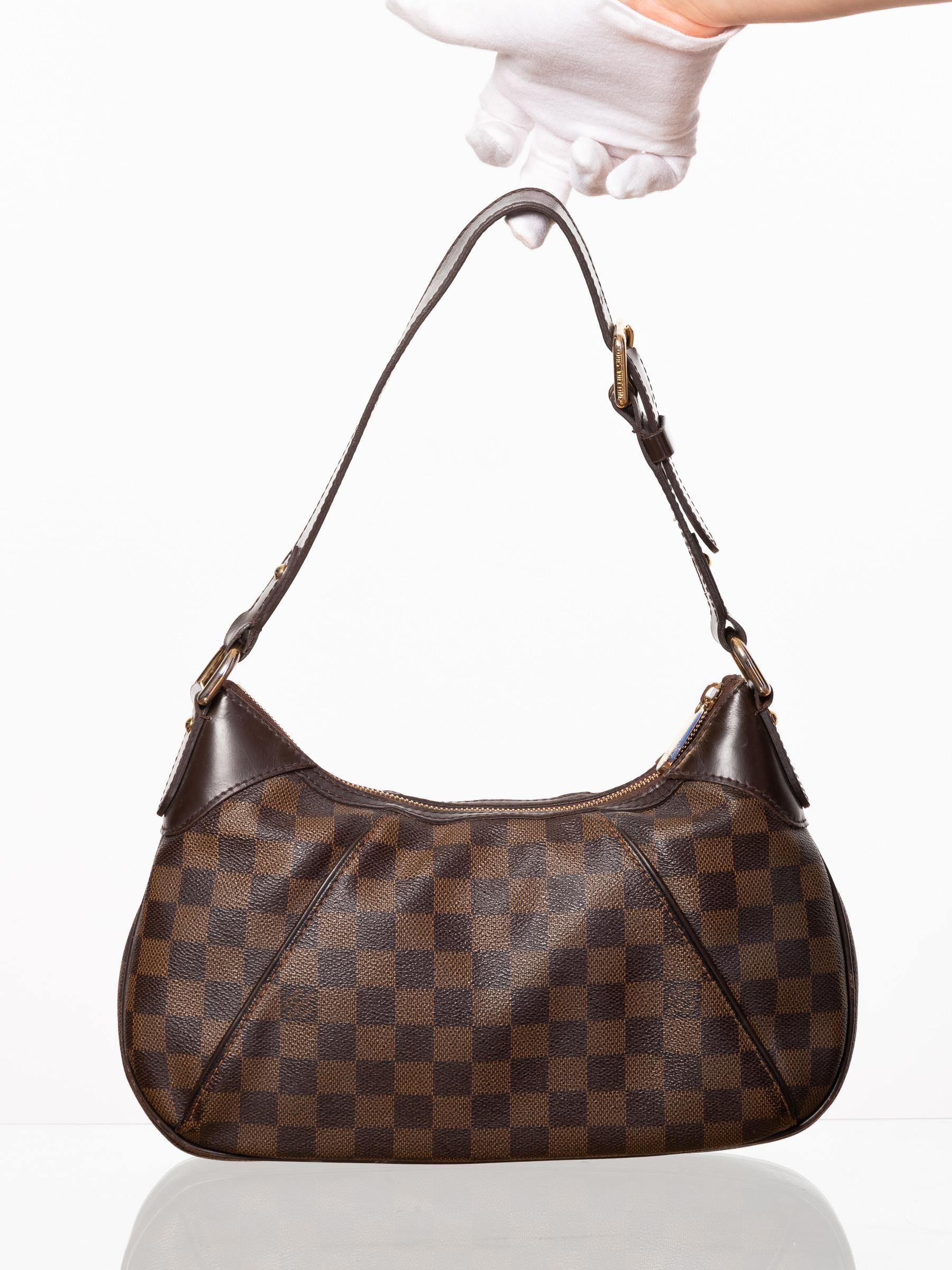 This bag is made with brown coated canvas with Damier Ebene pattern and finished with dark brown leather trim, a front brass plate, brass hardware, top zip closure, and red woven fabric interior lining. (Damier means checkerboard in French)

COLOR: