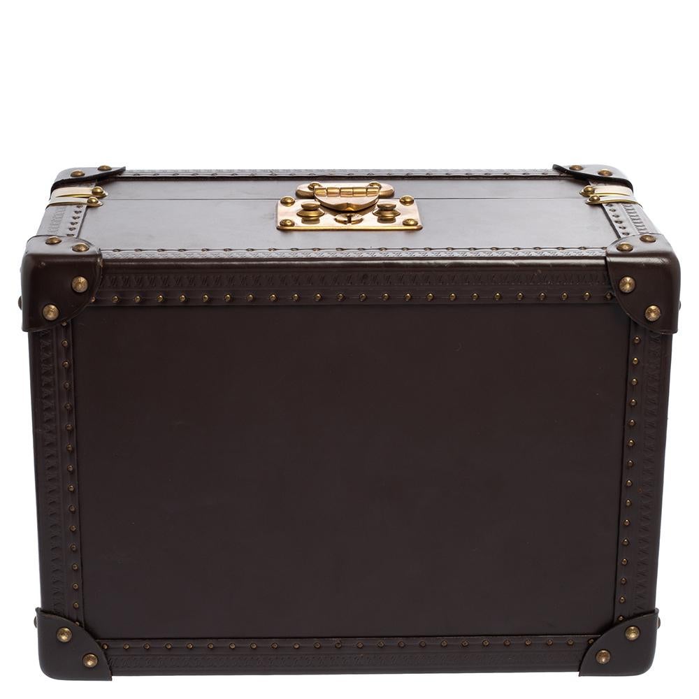 A vintage-inspired, luxurious piece, the jewelry box by Louis Vuitton is crafted from quality leather in a classic brown hue. It features a boxy silhouette with gold-tone metal detailing all over. The signature lock at the front open to a spacious