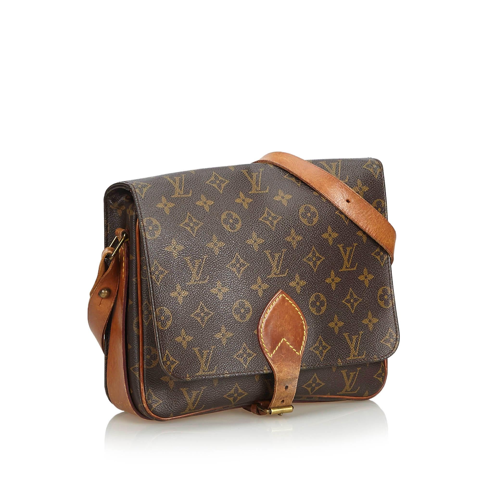 The Cartouchiere GM features a monogram canvas body, an adjustable leather strap, a front flap with a belt buckle closure, and an interior open compartment. It carries as B condition rating.

Inclusions: 
This item does not come with