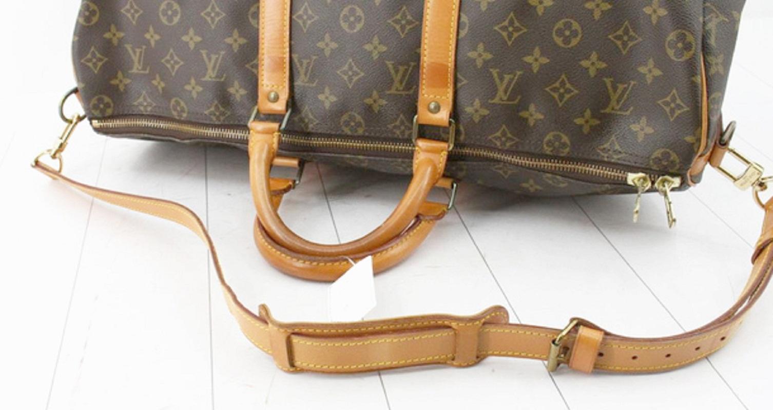 Brown and tan Monogram coated canvas Louis Vuitton Keepall Bandouliere 50cm with gold-tone hardware, tan vachetta leather trim, dual rolled top handles, brown canvas lining, single interior compartment and two-way zip closure at top. Detachable