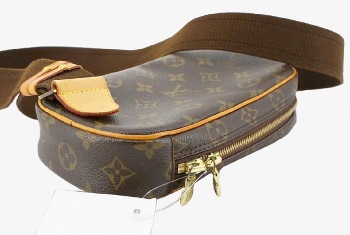 Brown and tan monogram coated canvas Louis Vuitton Pochette Gange bag with gold-tone hardware, tan vachetta leather trim, adjustable woven shoulder strap, slit pocket at front, brown canvas lining, single interior compartment and zip closure at
