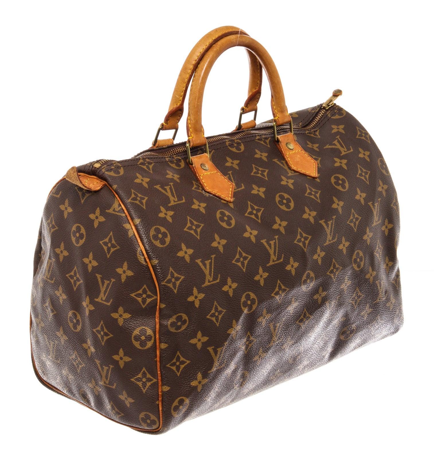 Brown and tan monogram coated canvas Louis Vuitton Speedy 35 with brass hardware, tan vachetta leather trim, dual-rolled handles, brown canvas lining, single slit pocket at interior wall, and zip closure at top. Please note: the leather part of the