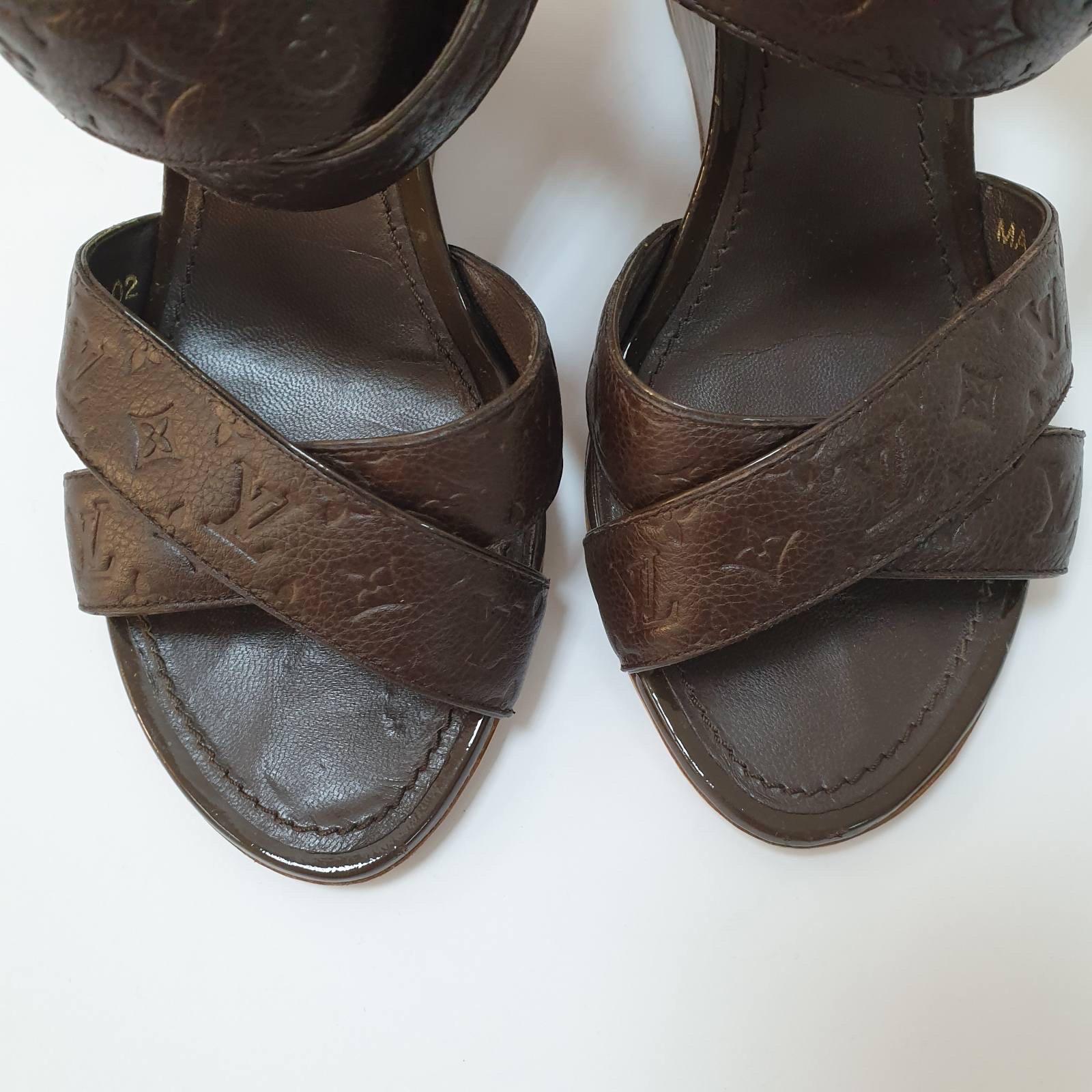 Eleva il tuo stile con questi autentici sandali con zeppa Kalahari di Louis Vuitton! Realizzati in lussuosa pelle marrone con monogram in rilievo, questi sandali open-toe sono il pezzo forte perfetto.

Nota bene: questi sandali sono in buone