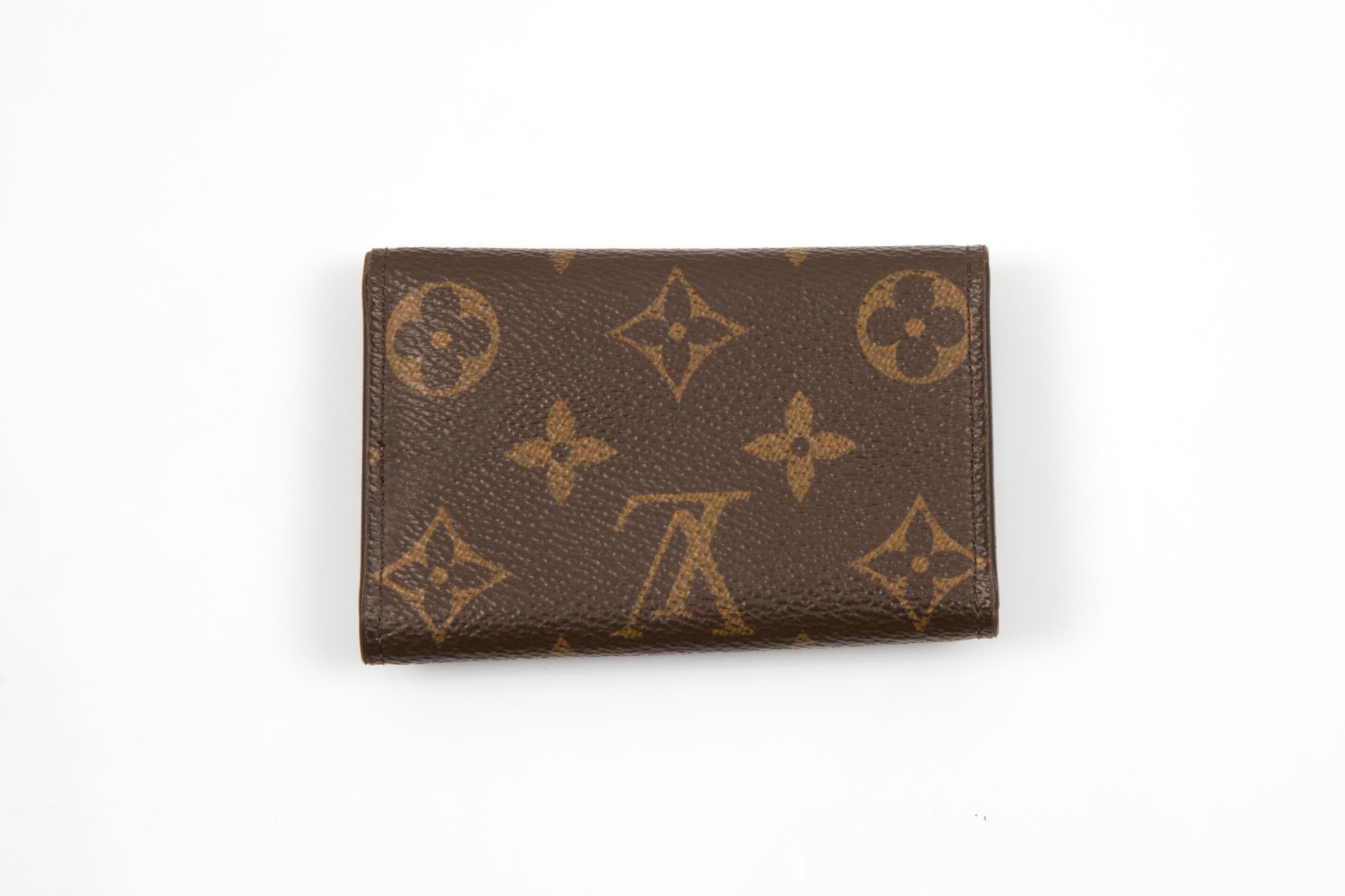 Porte-clés à six crochets Monogram de Louis Vuitton Brown avec un design à trois volets, une fermeture à bouton-pression avec logo (ne fermant pas correctement), des accessoires dorés, des crochets internes pour les clés, un cachet interne avec