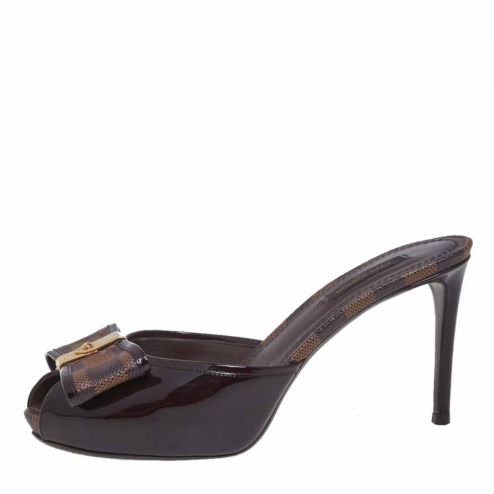 These fabulous sandals from Louis Vuitton are set on platforms and 9 cm heels. They have been crafted from brown patent leather and the signature Damier Ebene canvas and styled with peep-toes and trendy bows on the uppers. They are complete with