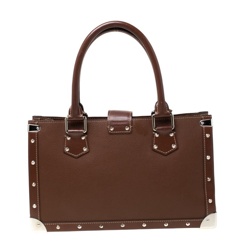 Louis Vuitton's Le Fabuleux bag looks nothing like a regular Louis Vuitton bag! Rectangular in shape the bag is crafted from brown Suhali leather and has stud embellishments. It features dual top handles, a front zip pocket, and a S lock closure.
