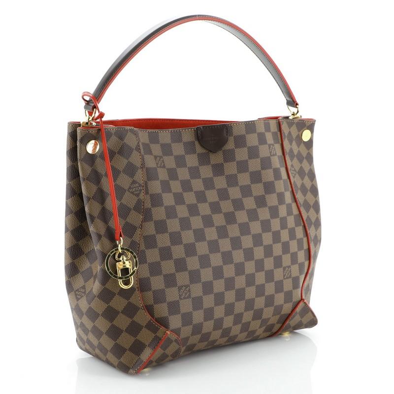 This Louis Vuitton Caissa Hobo Damier, crafted from damier ebene coated canvas, features a looping handle with anchors, leather trim, protective base studs, and gold-tone hardware. It opens to a red microfiber interior with zip and slip pockets.