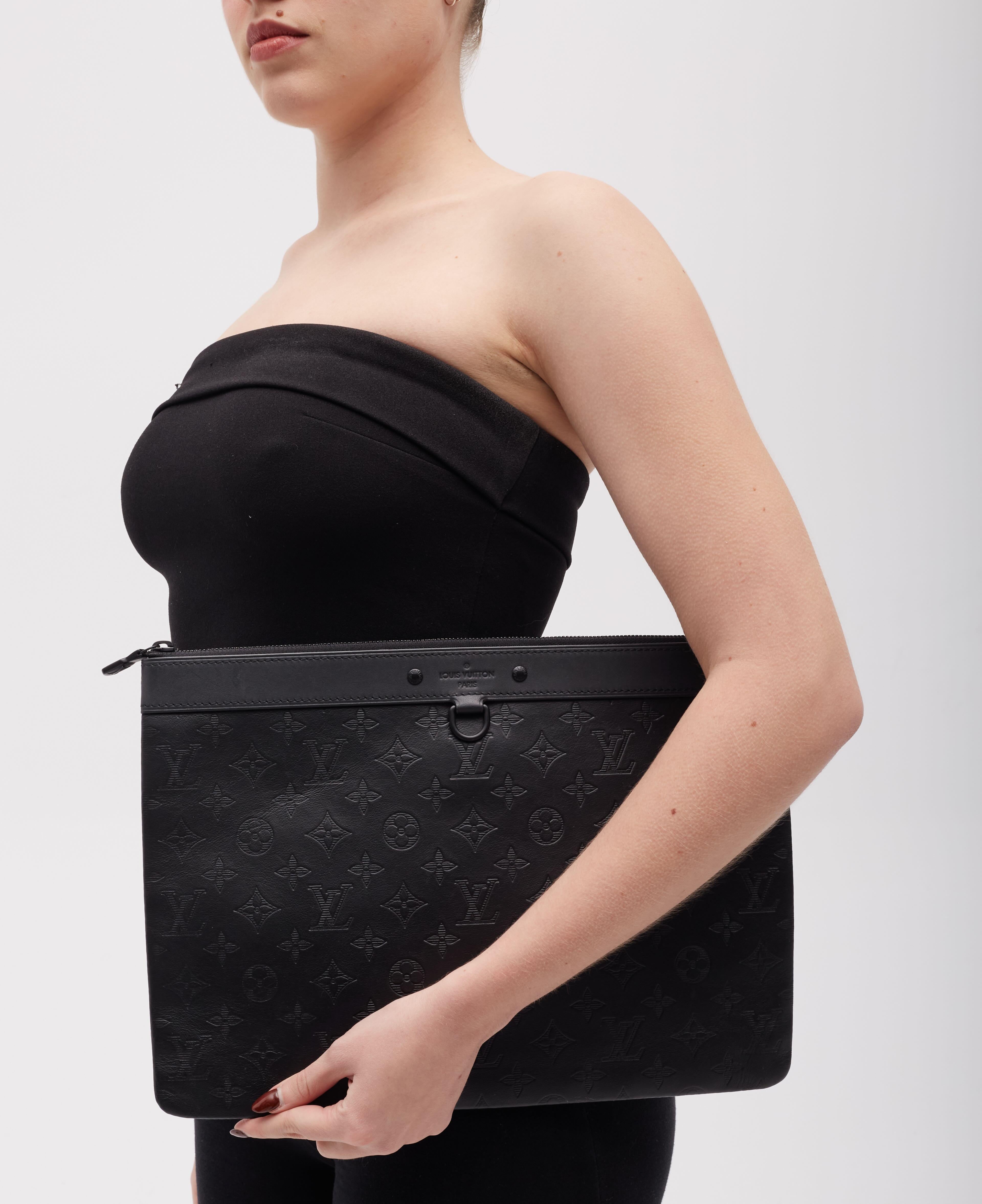 This pouch bag is crafted from black calfskin leather, featuring the Louis monogram embossing throughout. It is equipped with a black top zipper and opens to a black fabric interior, complete with a patch pocket for organization.

Color:
