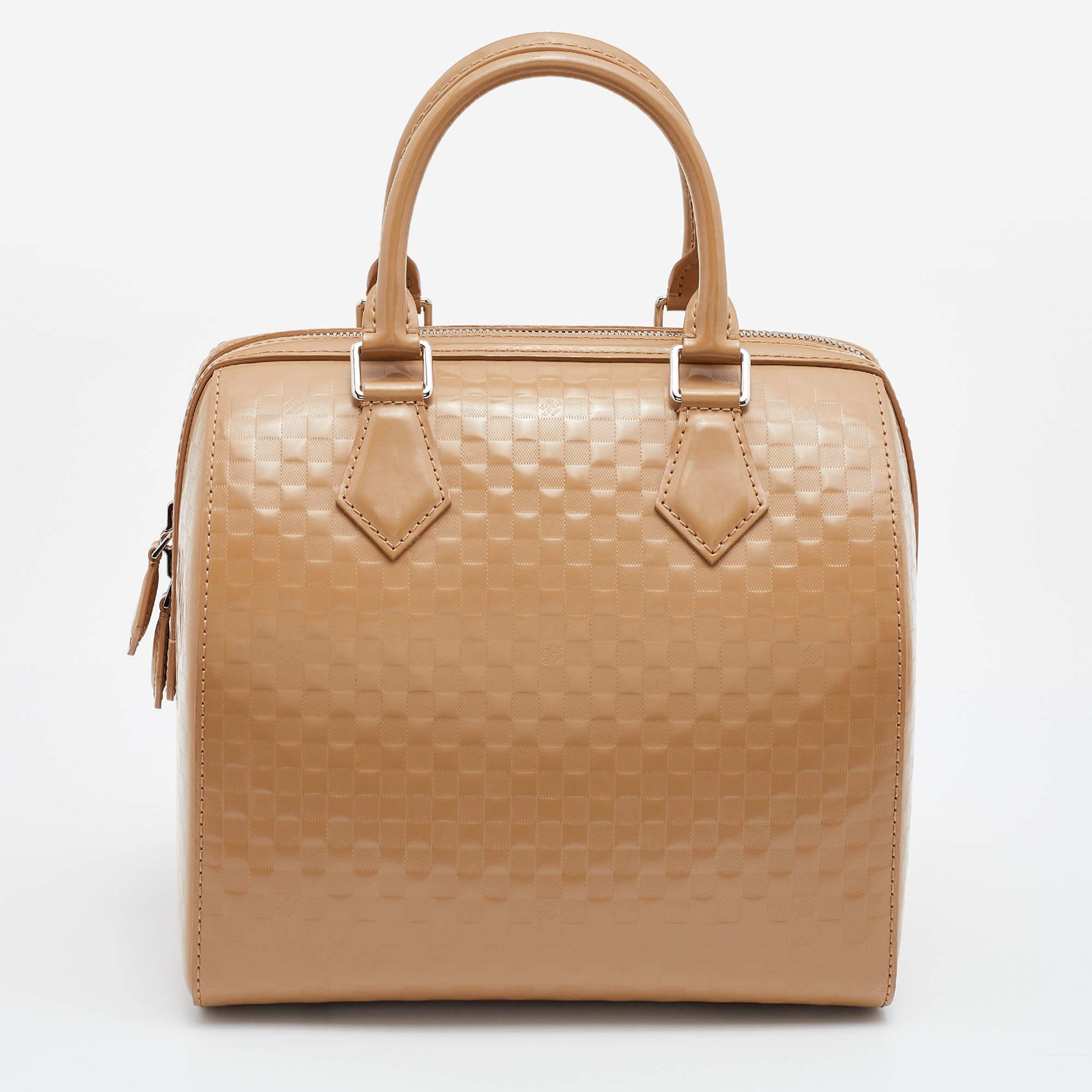 Don't miss the chance to own this gorgeous Louis Vuitton Speedy Cube MM bag. Crafted using Damier Facette Vernis, the bag comes in a camel tone paired with silver-tone metal. It's classy, timeless, and authentic!

Includes: Original Dustbag

