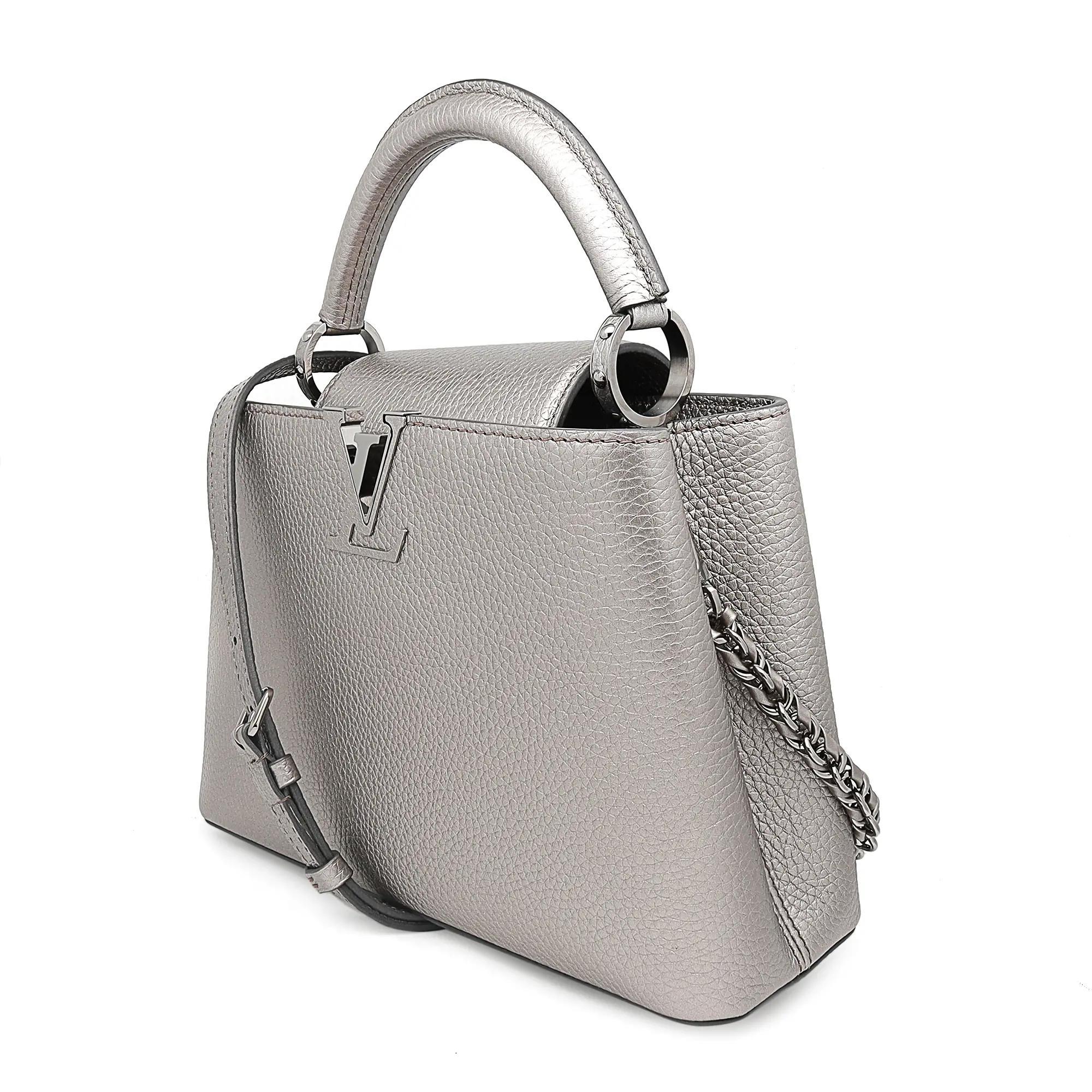 Louis Vuitton Capucines BB Metallic Grau Top Handle Handtasche. Diese schöne Umhängetasche besteht aus luxuriösem, strukturiertem Taurilloun-Leder in Metallic-Grau. Die Handtasche verfügt über einen einzelnen gerollten, lederverstärkten oberen Griff