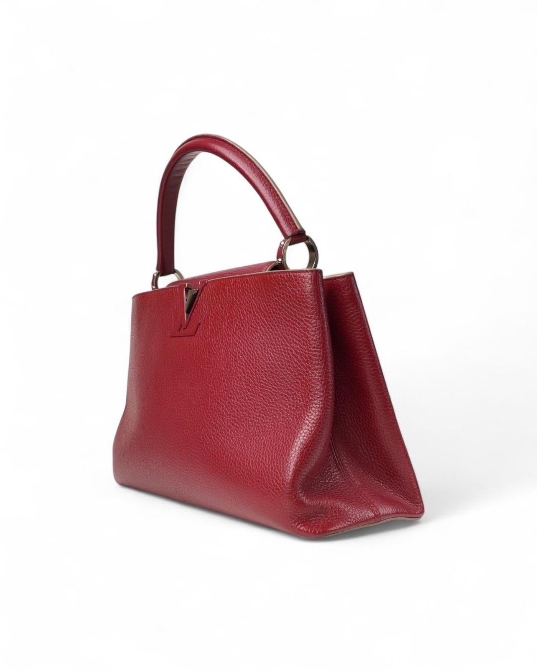 Borsa firmata Louis Vuitton, modello Capucines nella misura GM, realizzata in pelle martellata nella colorazione rossa con hardware argento. Dotée d'un chiusura ad incastro, internamente rivestita in tessuto fango con comode tasche, la borsa è