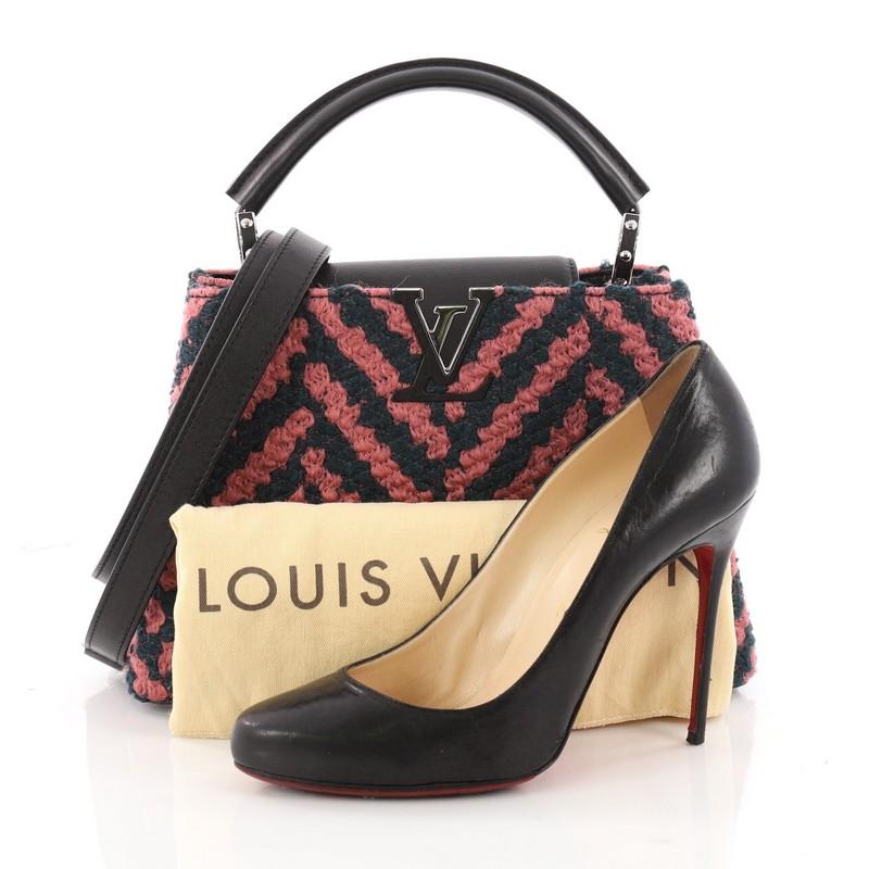 This authentic Louis Vuitton Capucines Handbag Chevron Tweed with Leather BB displays an exalted level of craftsmanship perfect for the stylish fashionista. Crafted from pink and blue chevron tweed with black leather, this ultra-chic petite bag