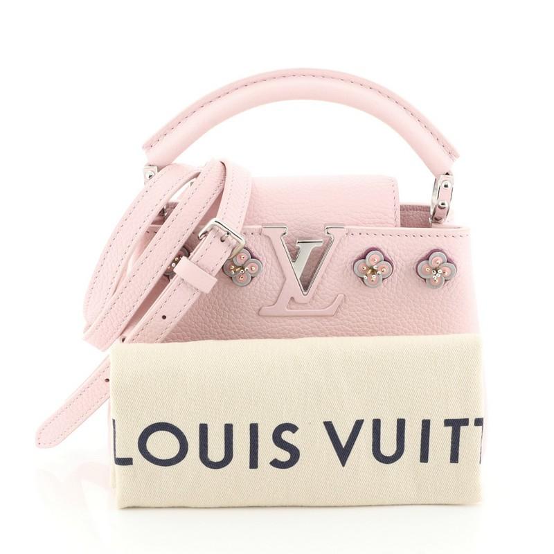 This Louis Vuitton Capucines Handbag Embellished Leather Mini, crafted in pink embellished leather, features a single loop leather handle secured by jewel-like rings, frontal flap, and silver-tone hardware. Its flap can be tucked inside to reveal