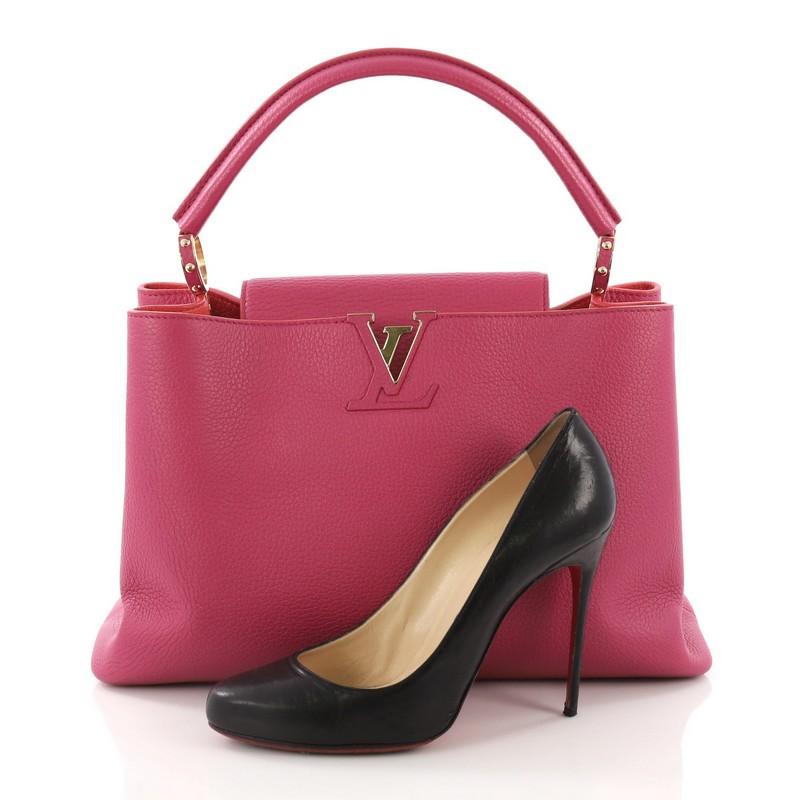 This Louis Vuitton Capucines Handbag Leather MM, crafted in pink leather, features a single loop leather handle secured by jewel-like rings, frontal flap, and gold-tone hardware. Its flap can be tucked inside to reveal the brand's logo and opens to