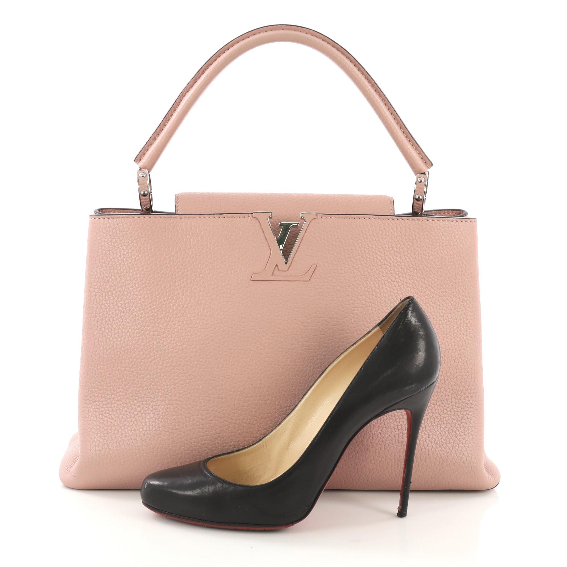 This Louis Vuitton Capucines Handbag Leather MM, crafted in pink leather, features a single loop leather handle secured by jewel-like rings, frontal flap, and silver-tone hardware. Its flap can be tucked inside to reveal the brand's logo and opens
