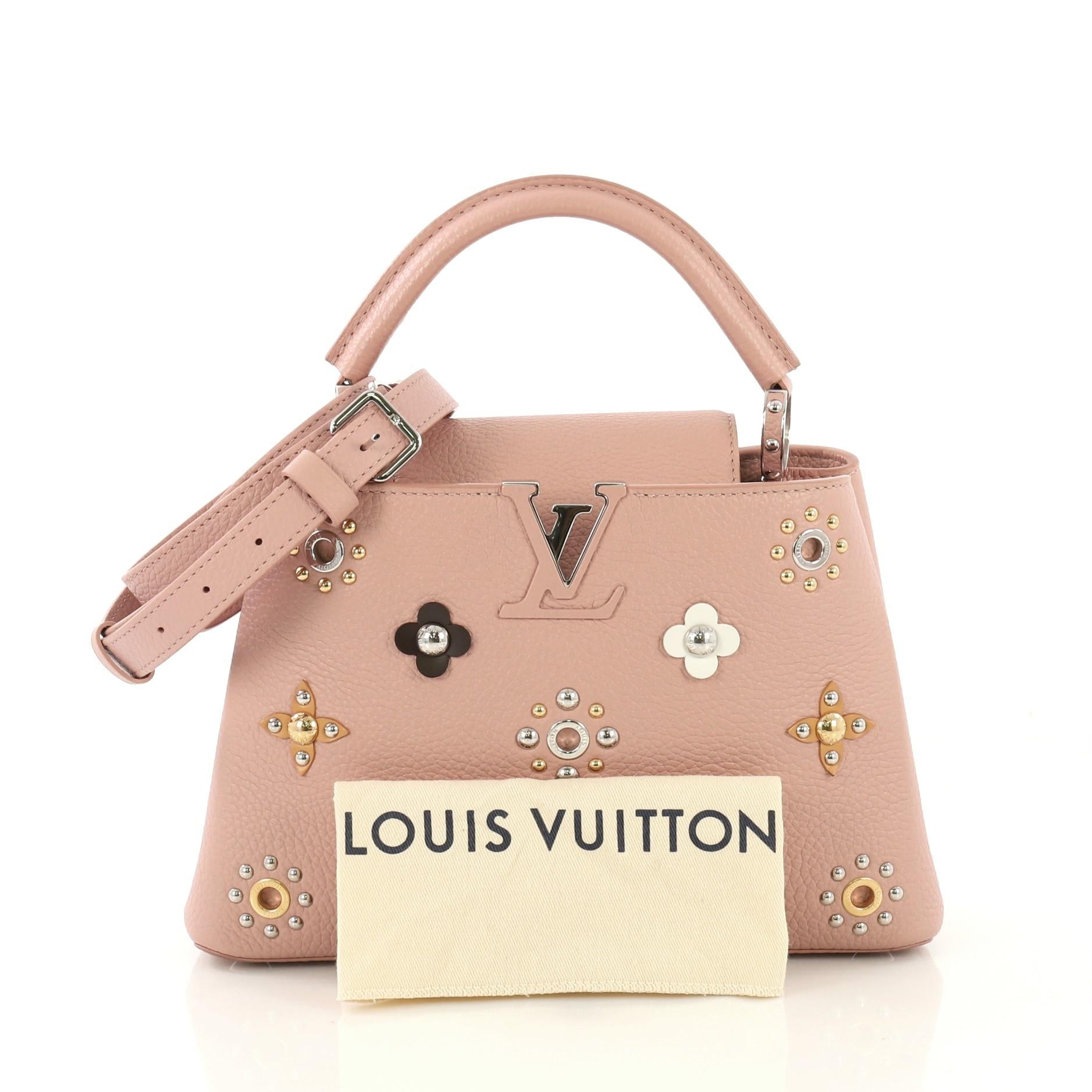 This Louis Vuitton Capucines Handbag Leather with Embellished Detail BB, crafted from pink leather with embellished detail, features a single loop leather handle with jewel-like rings, frontal flap with classic monogram flower, and silver-tone