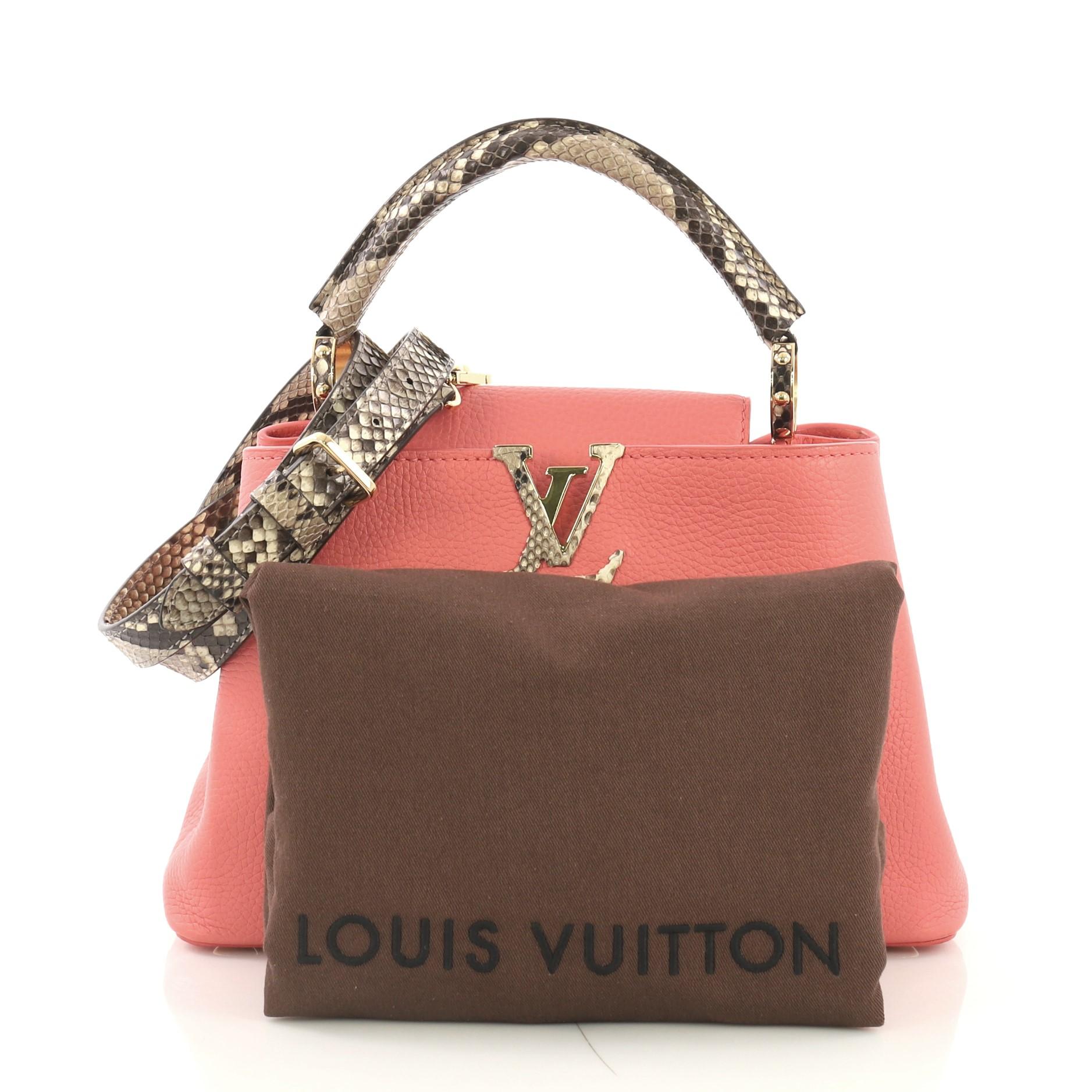 This Louis Vuitton Capucines Handbag Leather with Python BB, crafted in pink leather with genuine python, features a single rolled genuine python handle secured by jewel-like rings, frontal flap with the classic monogram flower, and gold-tone