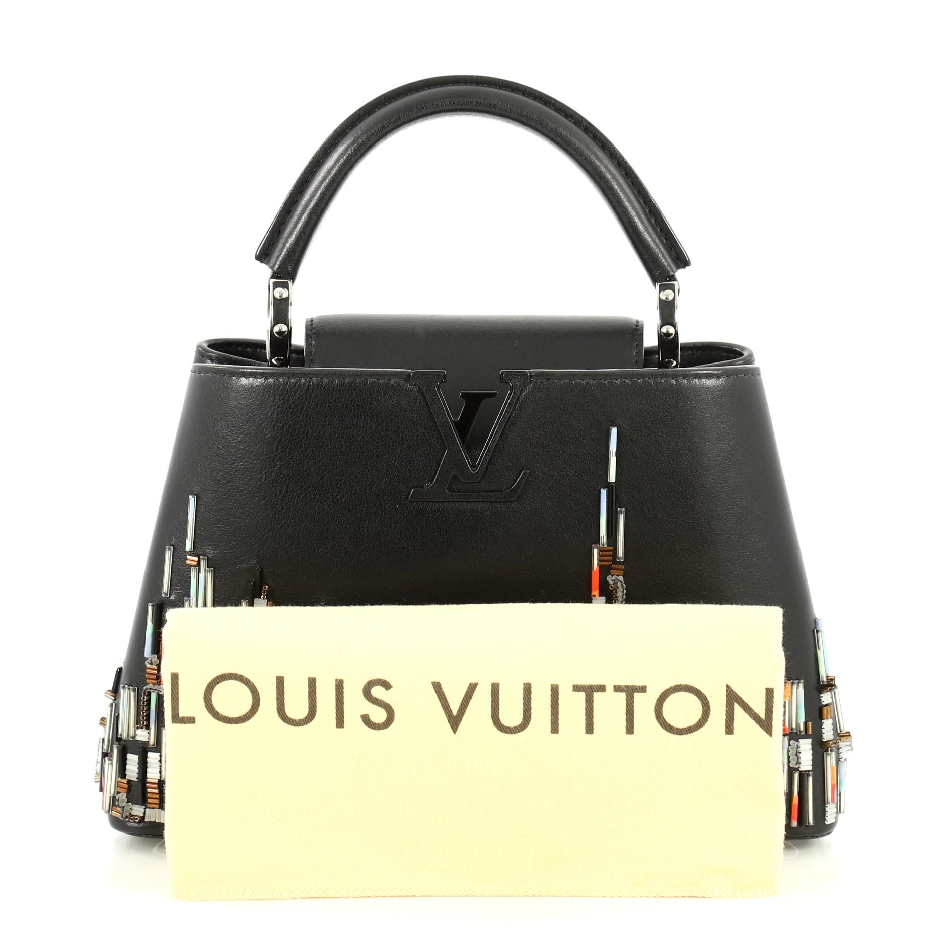 This Louis Vuitton Capucines Handbag Limited Edition City Beaded Leather BB, crafted from black beaded leather, features a single rolled leather handle, frontal flap with the classic monogram flower, and black and silver-tone hardware. Its flap