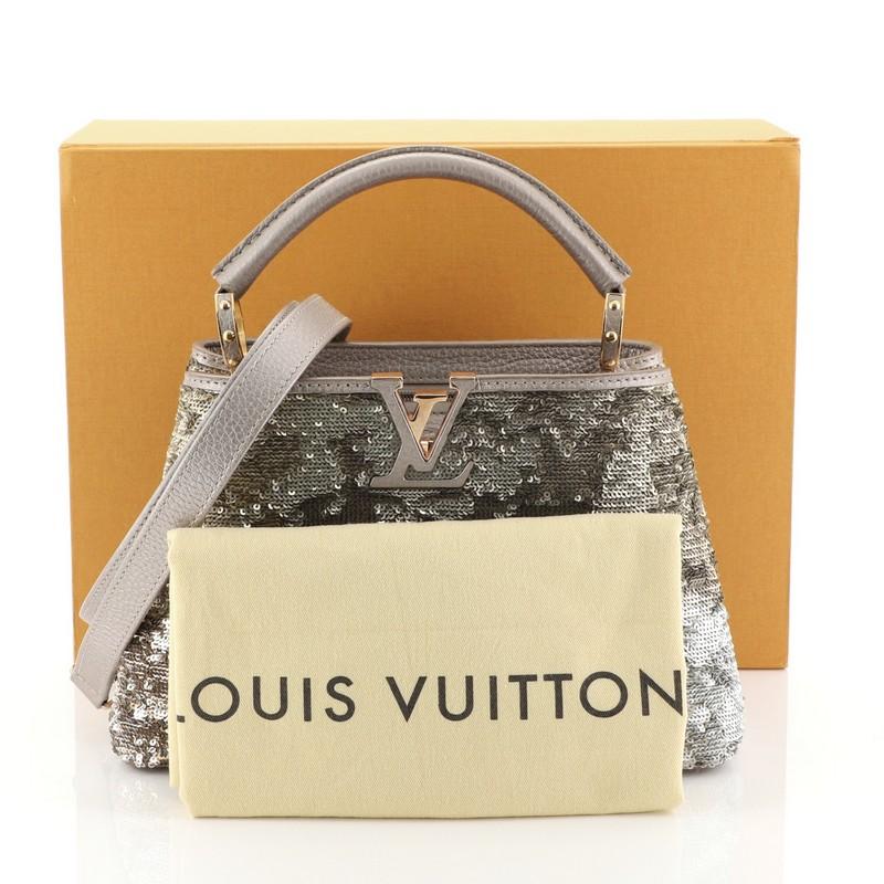 This Louis Vuitton Capucines Handbag Sequins BB, crafted from metallic gold leather and silver sequins, features a single rolled leather handle secured by jewel-like rings, frontal flap with classic monogram flower, and gold and rose gold-tone