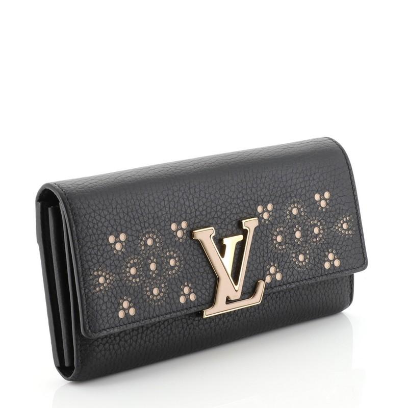 This Louis Vuitton Capucines Wallet Perforated Leather, crafted in black leather, features a signature LV logo in front, decorative perforations and gold-tone hardware. Its hidden snap button closure opens to a black leather interior with multiple