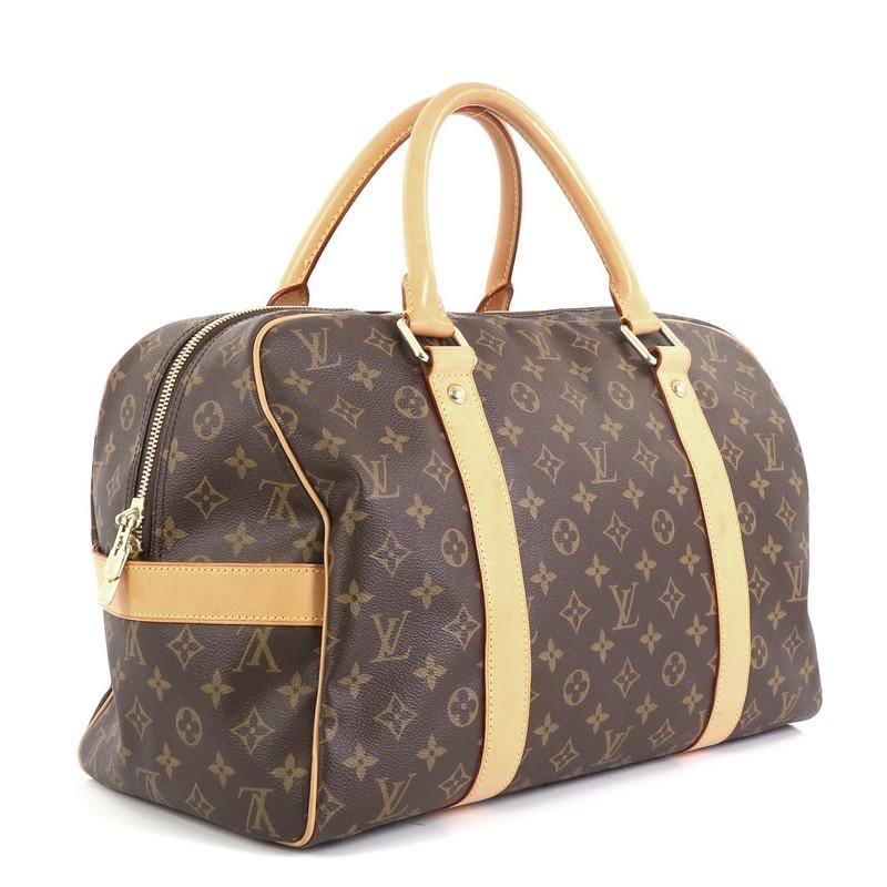 This Louis Vuitton Carryall Handbag Monogram Canvas, crafted in brown monogram coated canvas, features dual rolled handles, cowhide vachetta leather trim, protective base studs, and gold-tone hardware. Its top zip closure opens to a brown fabric
