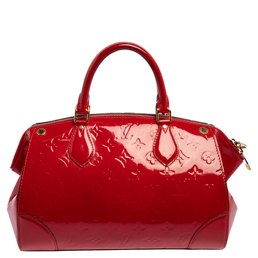 This elegant Santa Monica bag by Louis Vuitton will surely leave you spellbound. This red bag carries a structured body rendered in monogram Vernis leather with gold-tone studs and two top handles. A spacious fabric-lined interior completes the