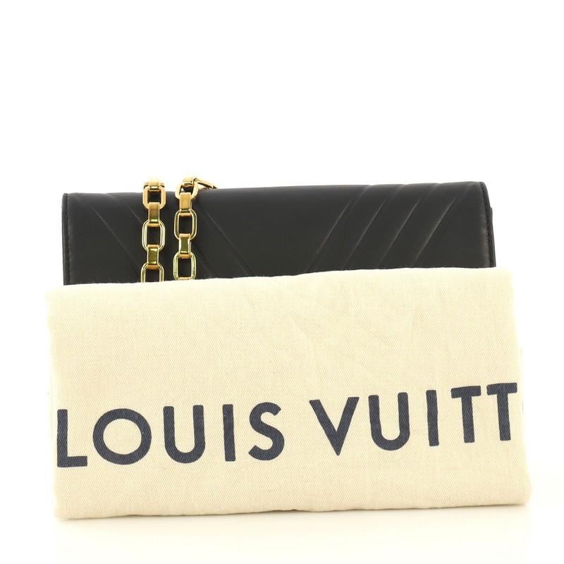 This Louis Vuitton Chain Louise Clutch Airy V Leather GM, crafted in black leather, features a chain link strap and gold-tone hardware. Its LV flip-lock clasp closure opens to a black microfiber interior with slip pocket. Authenticity code reads: