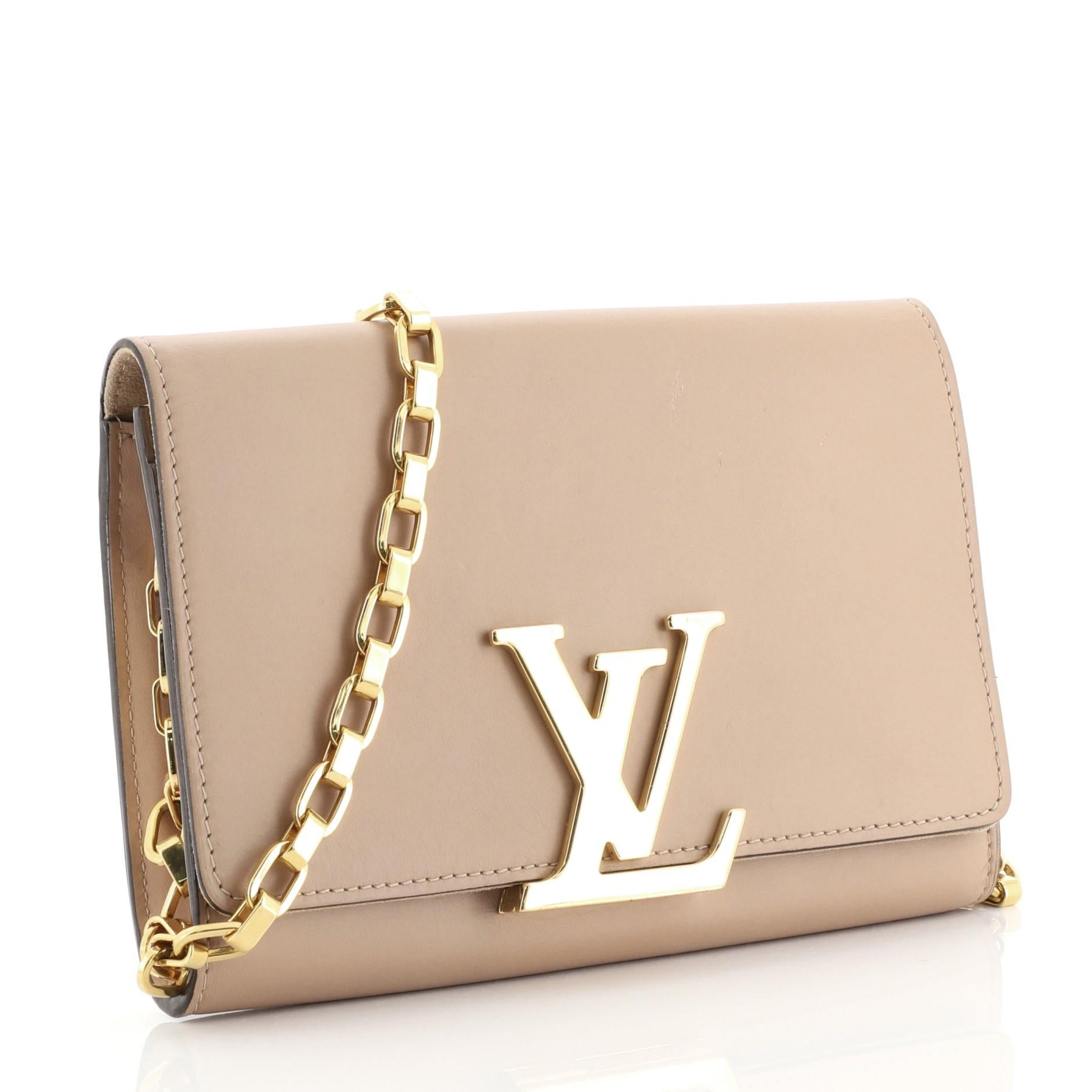 This Louis Vuitton Chain Louise Clutch Leather GM, crafted in neutral leather, features an oversized LV logo flip lock clasp closure, chain link strap and gold-tone hardware. Its flap opens to a neutral microfiber and leather interior with zip