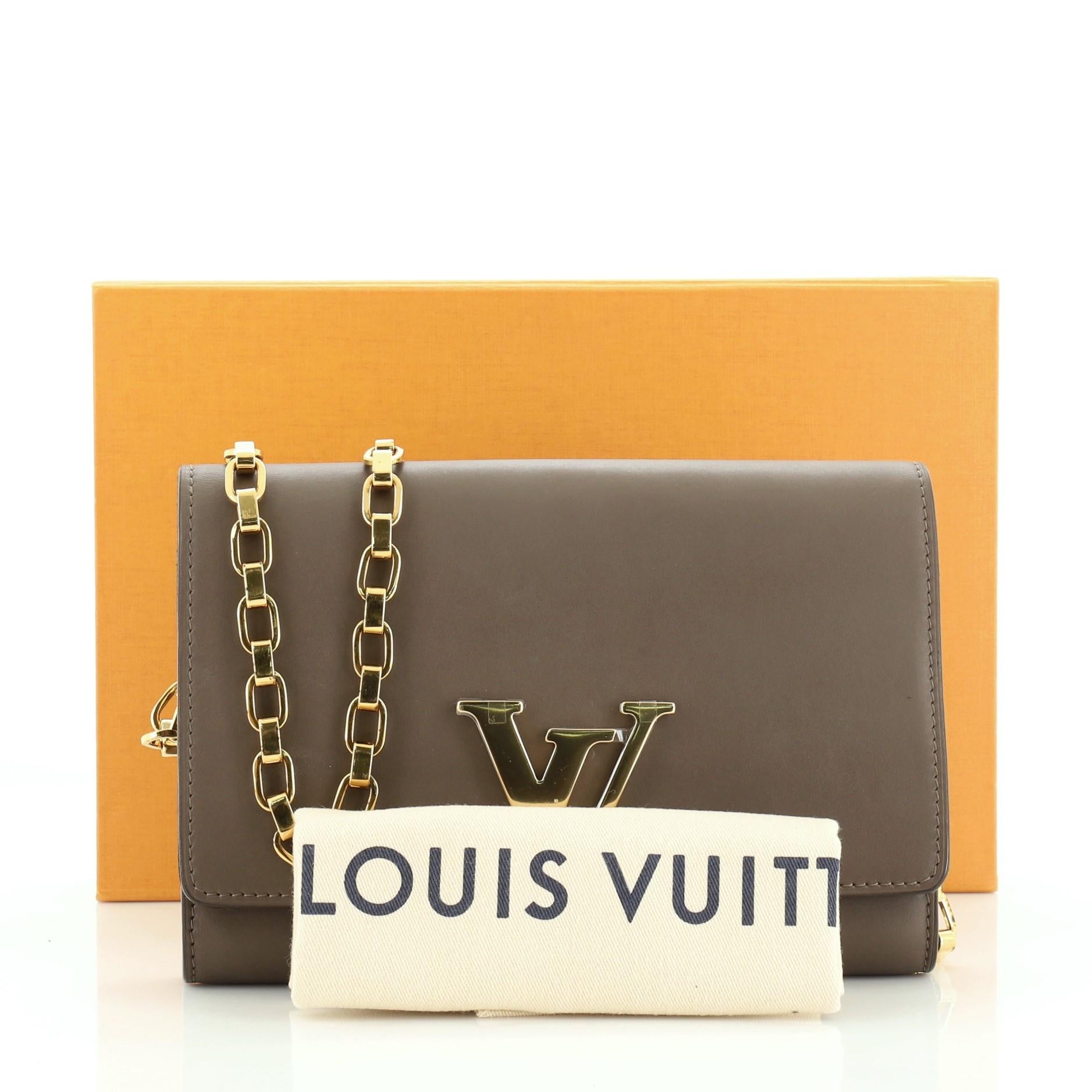 This Louis Vuitton Chain Louise Clutch Leather GM, crafted in brown leather, features an oversized LV logo flip lock clasp closure, chain link strap and gold-tone hardware. Its flap opens to a brown microfiber and leather interior with zip pocket
