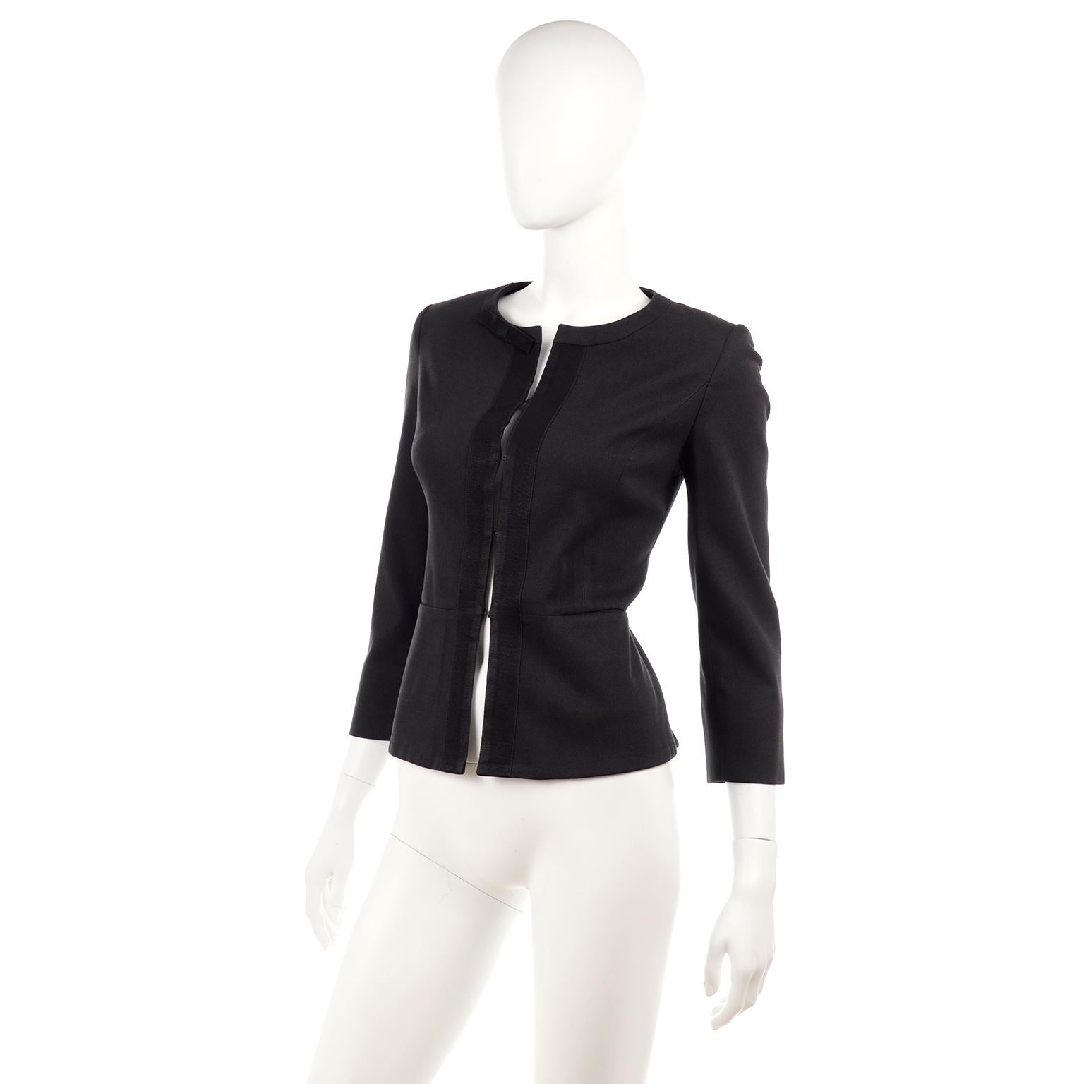 This is a gorgeous washed black or charcoal blazer jacket from Louis Vuitton Uniformes. It has 3/4 sleeves with a slit at the opening, and a grosgrain ribbon trim that creates a bow on the left side of the collar. It has subtle shoulder pads. It