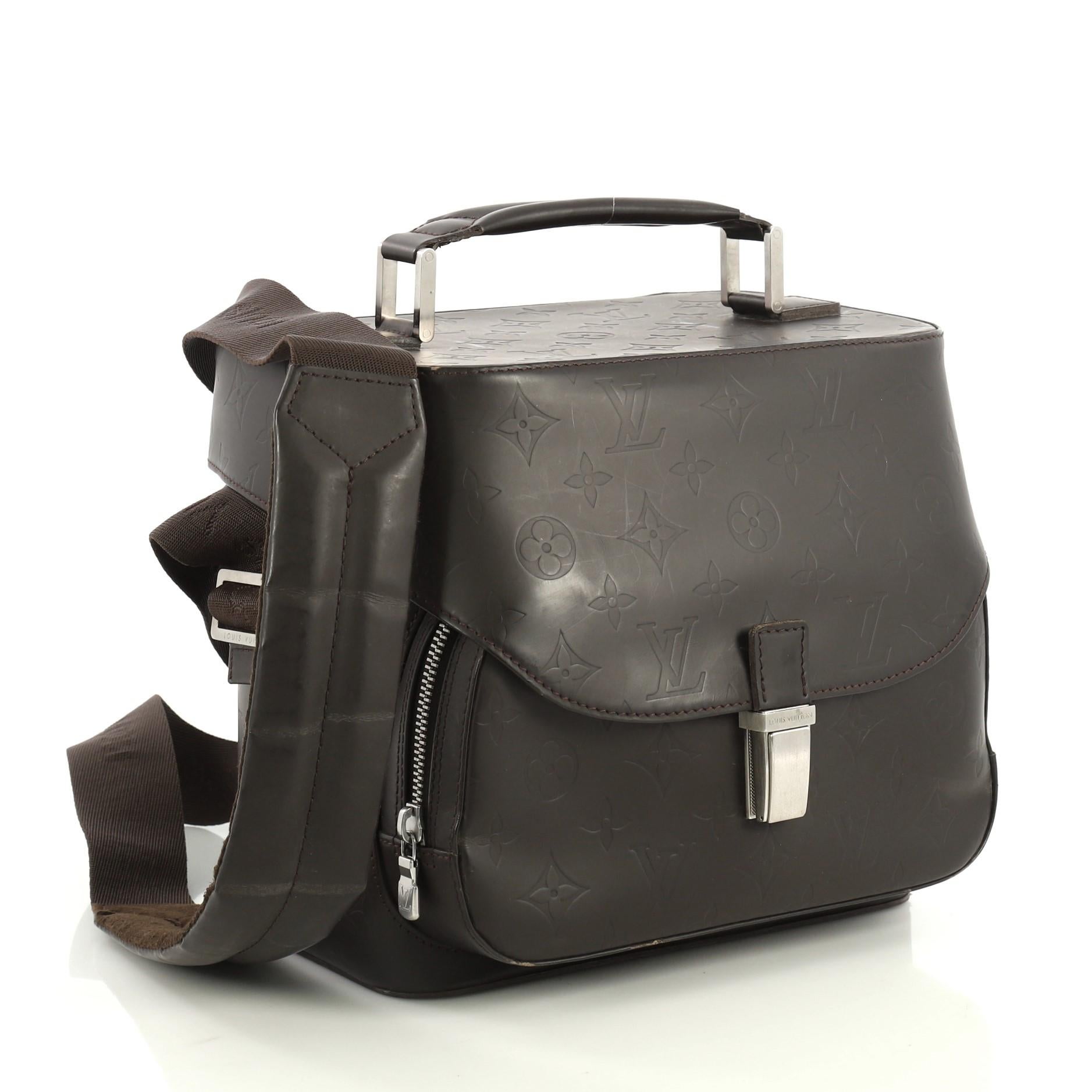 This Louis Vuitton Charly Camera Bag Monogram Glace Leather, crafted in brown monogram glace leather, features a flat leather handle, long adjustable shoulder strap, zip pocket under flap and matte silver-tone hardware. Its push-lock closure opens