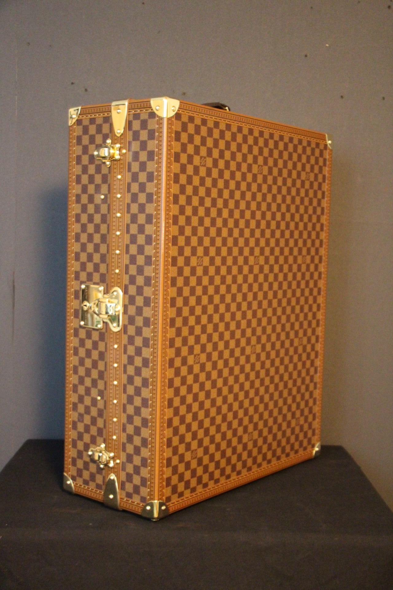 This trunk was a special order made in 2000's. It features checkers canvas, or damier ébène and stamped LV solid brass locks, corners and studs. On the top is the leather handle, Louis Vuitton embossed.
Inside is all brown suedine featuring 12