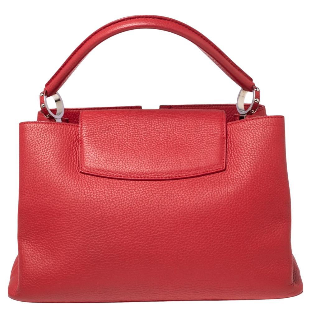 It is every woman's dream to own a Louis Vuitton handbag as appealing as this one. This Capucines MM bag is made from Cherry Taurillon leather on the exterior with a signatory LV accent perched on the front. It has dual handles, silver-toned