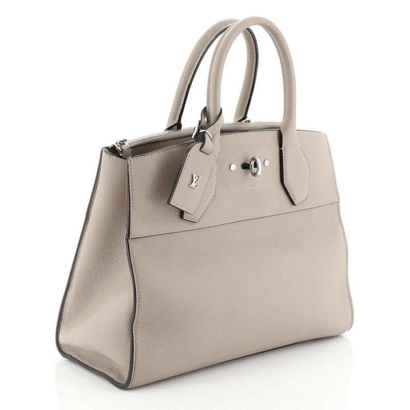 This Louis Vuitton City Steamer Handbag Leather MM, crafted from neutral leather, features dual rolled leather handles, front central lock with LV stamped logo, and silver-tone hardware. Its hook closure opens to a neutral leather interior with a