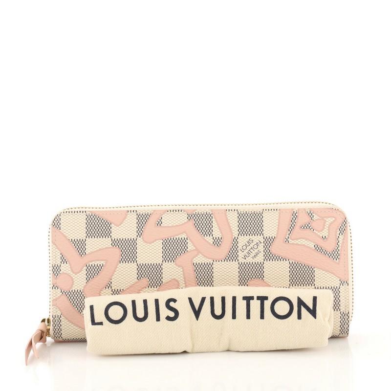 This Louis Vuitton Clemence Wallet Limited Edition Damier Tahitienne, crafted from damier azur coated canvas, features gold-tone hardware. Its all-around zip closure opens to a pink leather interior with multiple card slots, slip pockets, gusseted