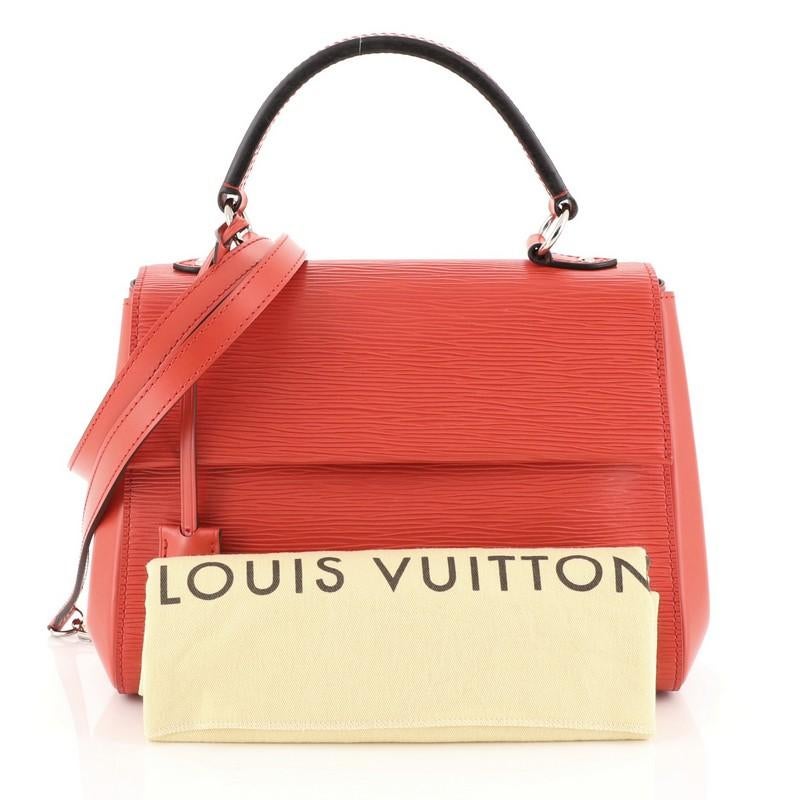 This Louis Vuitton Cluny Top Handle Bag Epi Leather BB, crafted in red epi leather, features a leather top handle, protective base studs, and silver-tone hardware. Its magnetic closure opens to a brown microfiber interior with zip and slip pockets.