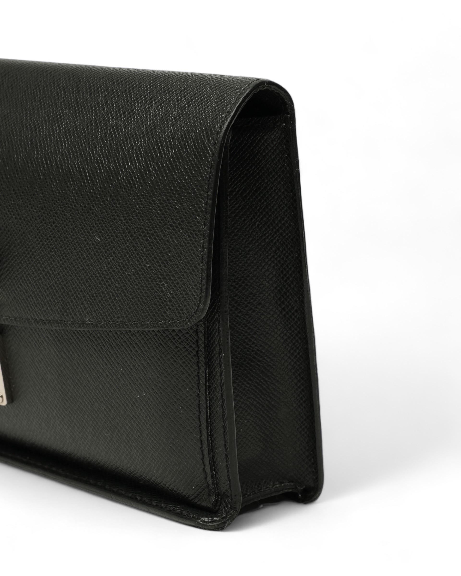 Clutch firmata Louis Vuitton, modello Belaia, misura MM, realizzata in pelle taiga nera con hardware argentati. Dotata di una patta frontale con chiusura ad incastro, internamente rivestita in pelle tono su tono, capiente per l’essenziale. Munita di