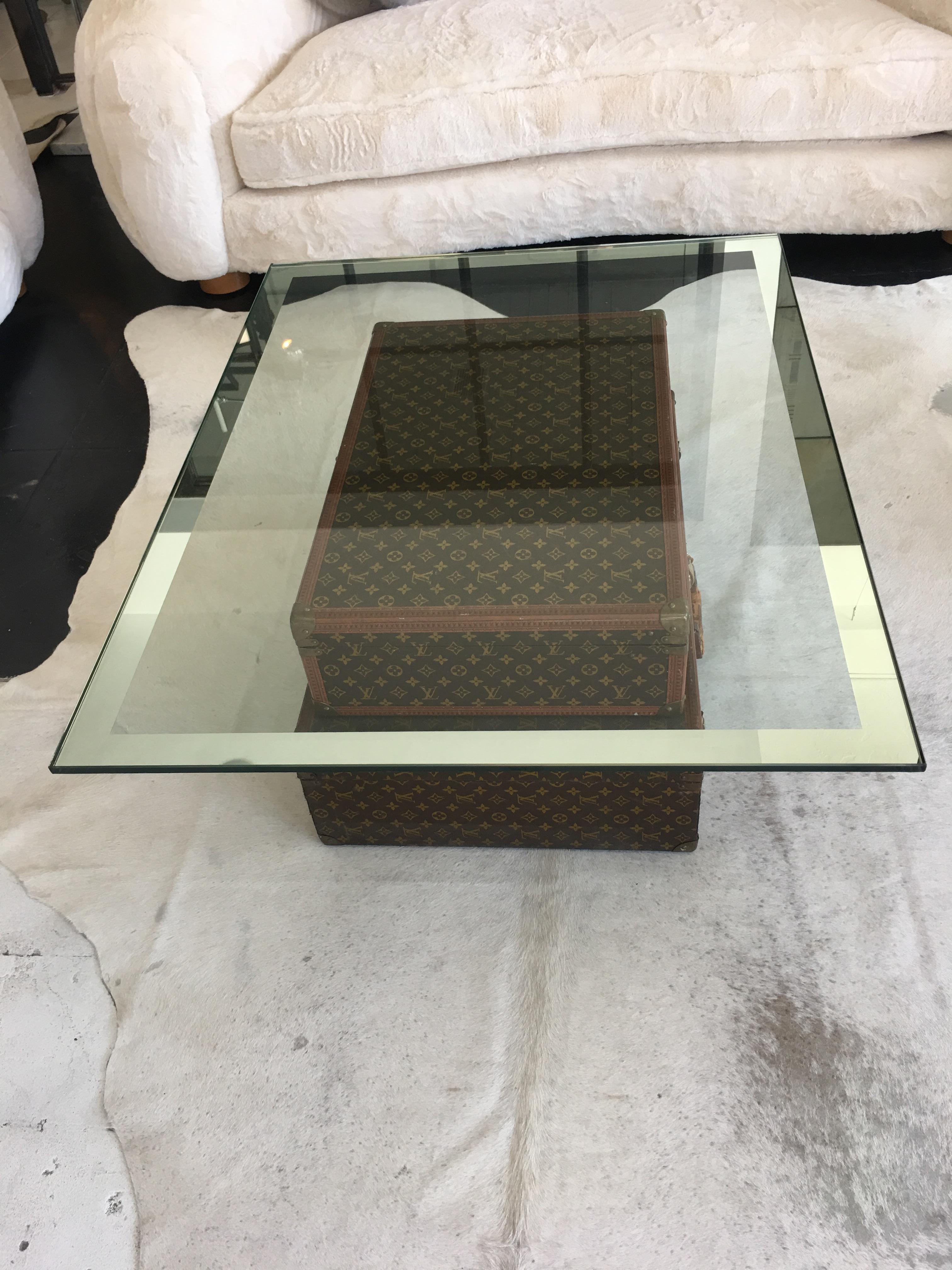 Two vintage 1950s Louis Vuitton trunks converted into a coffee table. Half-inch thick glass top with 2-inch mirror border.