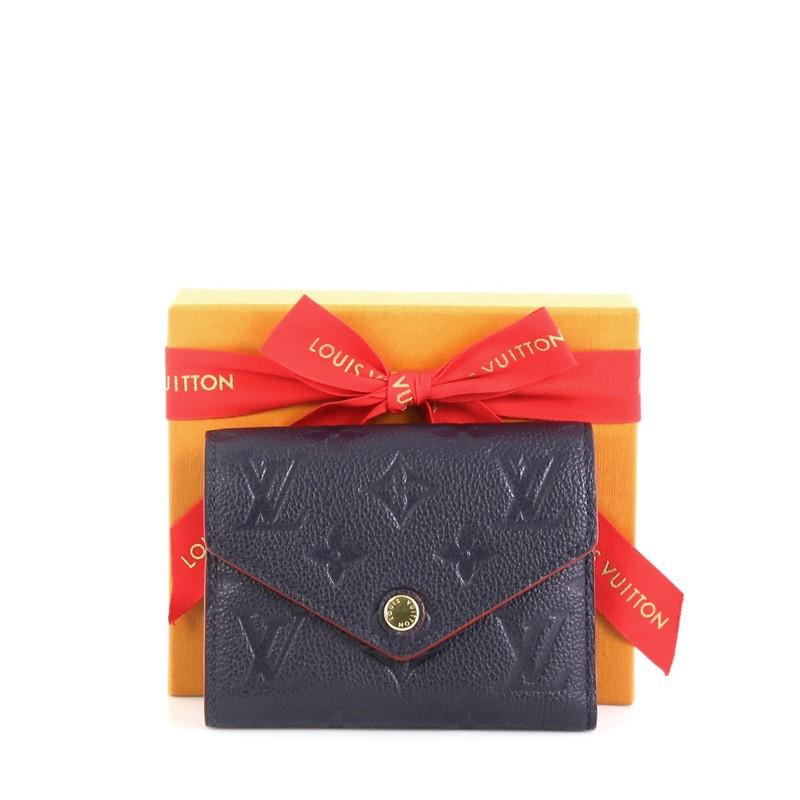 This Louis Vuitton Compact Victorine Wallet Monogram Empreinte Leather, crafted in blue monogram empreinte leather, features gold-tone hardware. Its press-stud closure opens to a blue leather interior with multiple card slots, zip pocket and bill