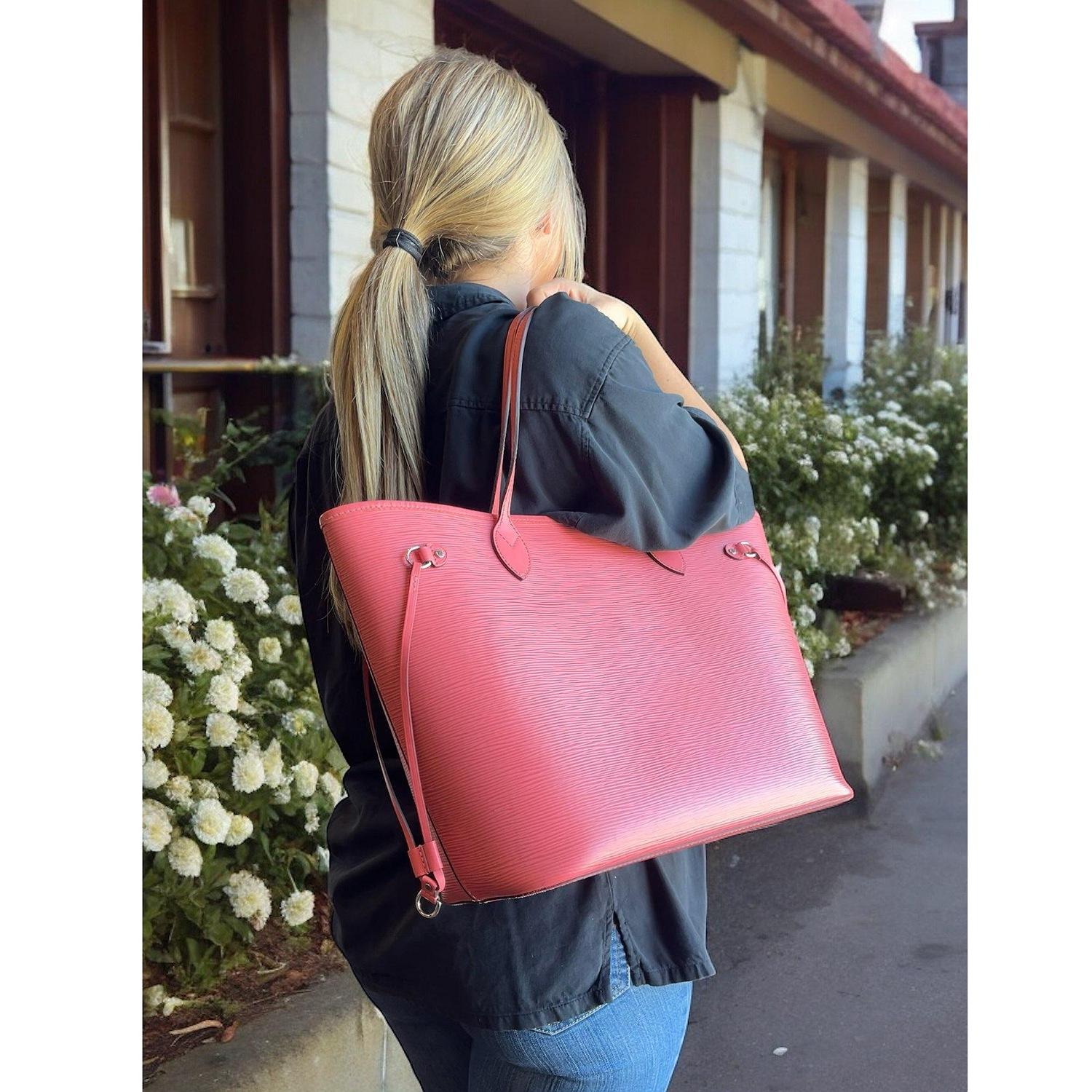 This stylish tote is crafted of signature Epi textured leather in coral in the medium size. The tote features smooth cowhide leather top strap handles, trim and side cinch cords with polished silver hardware. The wide top is open to a matching suede