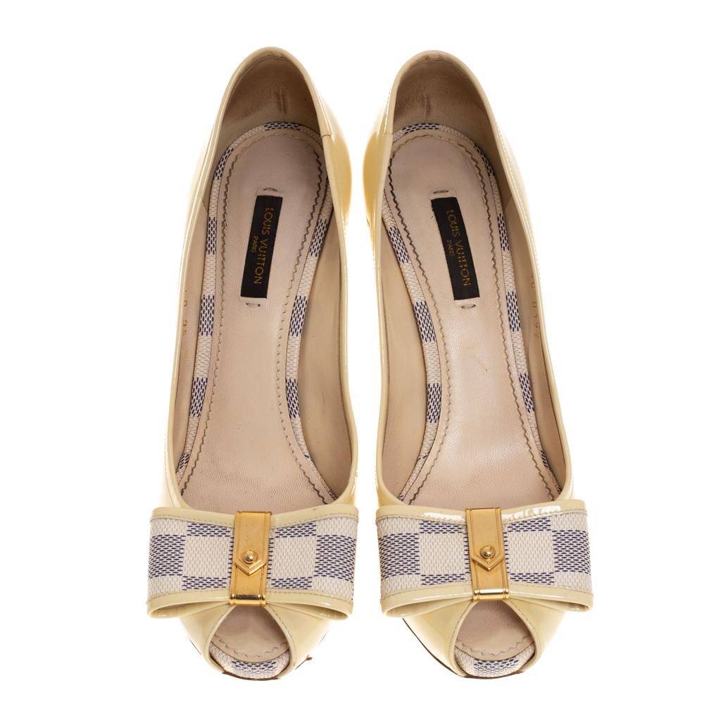 Make a bold style statement as you flaunt these Louis Vuitton pumps. They come crafted from cream patent leather and feature a peep-toe silhouette. They have been styled with the signature Damier Azur canvas bows on the uppers and endowed with