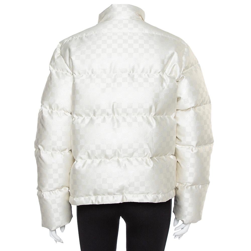 Stay warm in this ultra-stylish puffer jacket by Louis Vuitton. Designed in a fashionable silhouette with the signature Damier pattern all over, the cream quilted jacket, tailored from quality materials, will look great with your winter separates.