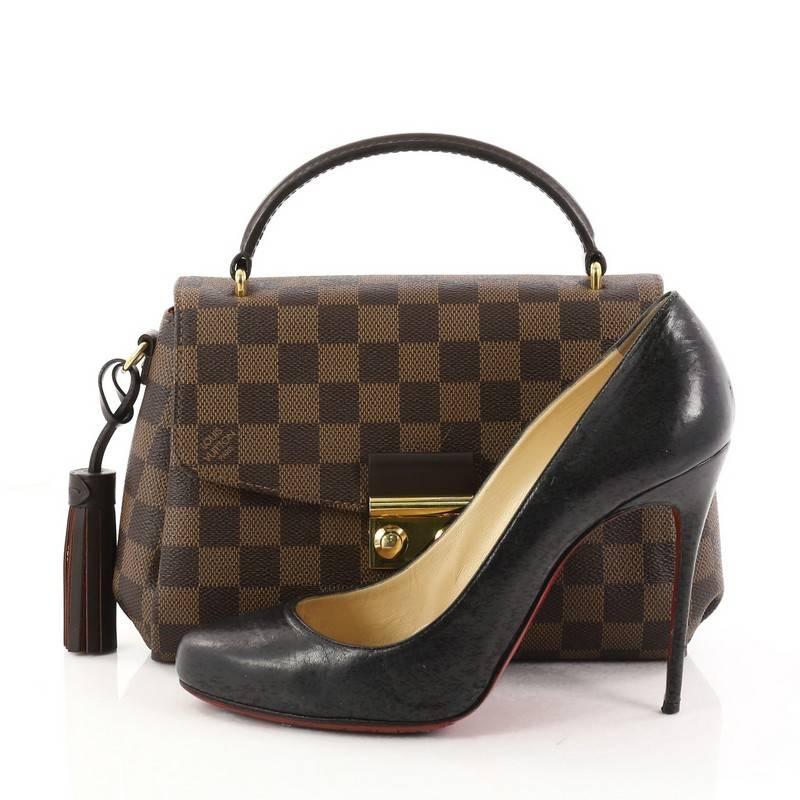 This authentic Louis Vuitton Croisette Handbag Damier is a marvelous bag ideal for everyday convenience. Crafted in damier ebene coated canvas, this stylish bag features dark brown leather top handle and gold-tone hardware accents. It opens to a red