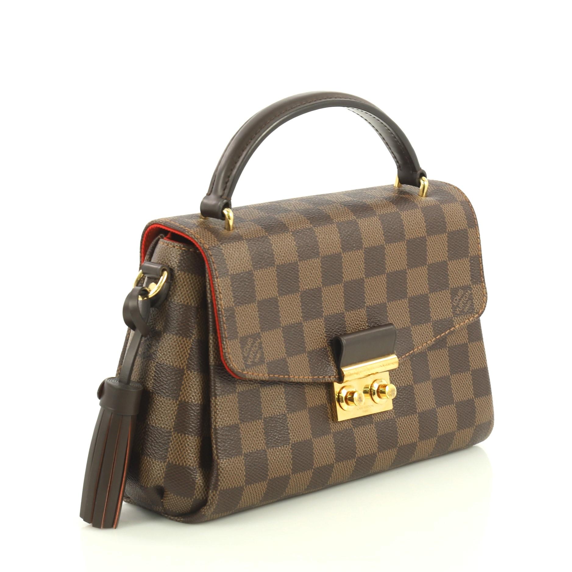 This Louis Vuitton Croisette Handbag Damier, crafted in damier ebene coated canvas, features a leather top handle and gold-tone hardware. It opens to a red fabric interior with slip pocket. Authenticity code reads: FL1128. 

Estimated Retail Price: