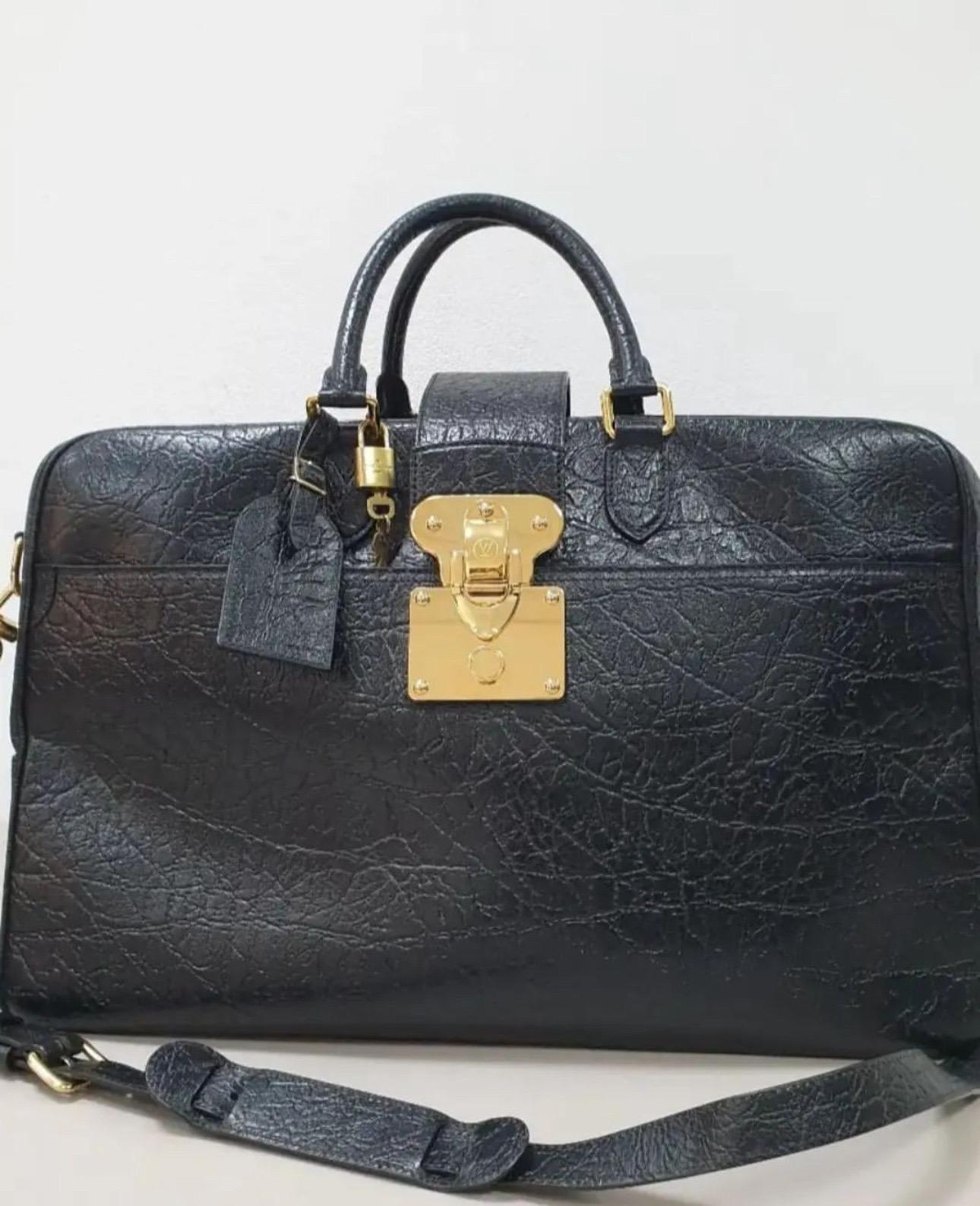 LOUIS VUITTON Calfskin Duffle Bag in Black. 
This stylish bag is crafted of calfskin leather in black. 
It features a top lock, polished brass hardware, a short top handle strap, and an optional shoulder strap.

Height: 13.39 in (34 cm)Width: 9.45